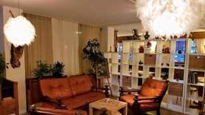 A cozy living room with a leather sofa, a wooden coffee table, and a bookshelf filled with decorative items. - Hôtel des Haudères (Evolène)