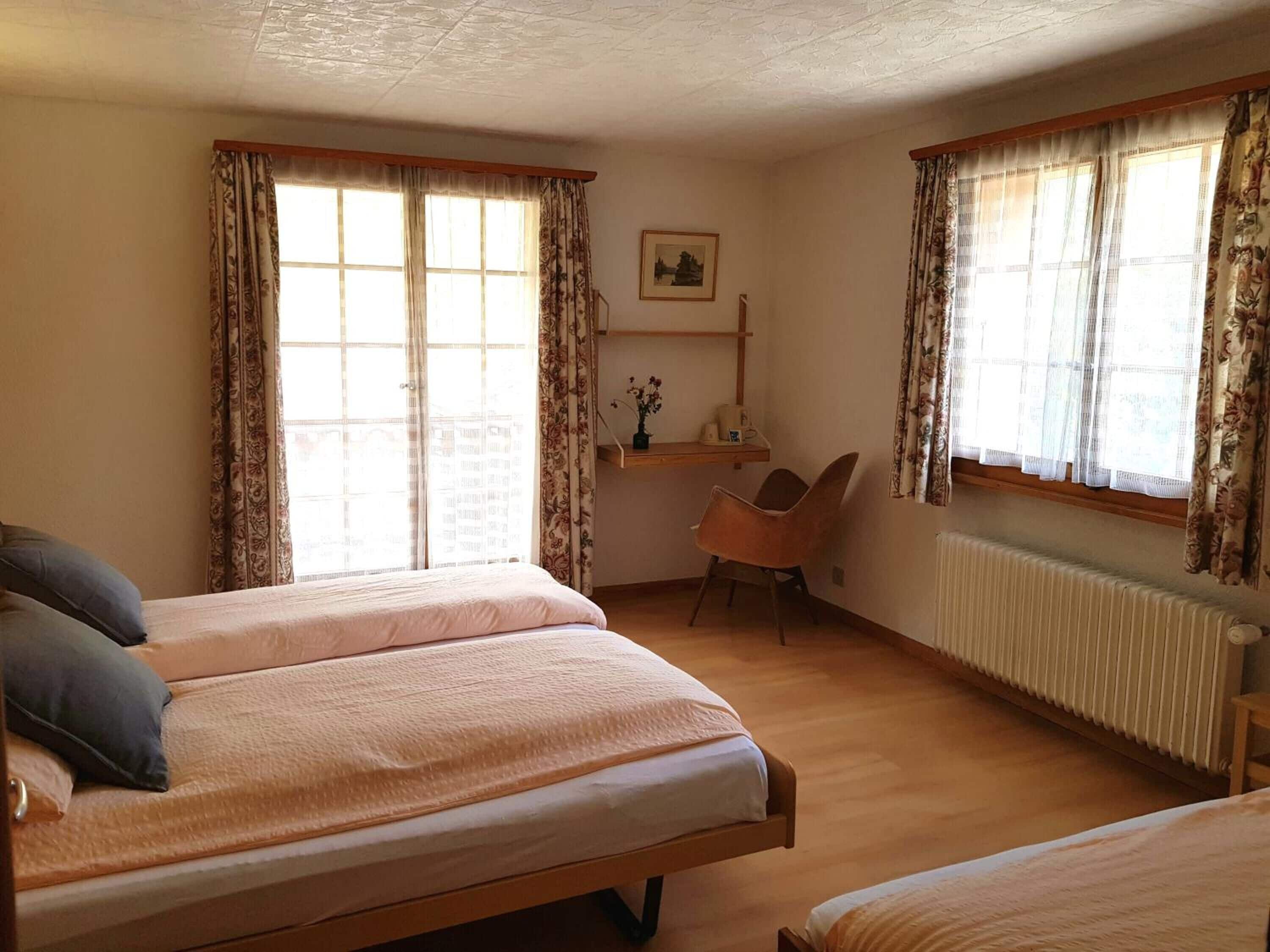 Ein Schlafzimmer mit zwei Betten, einem Schreibtisch, einem Stuhl und einer Heizung.