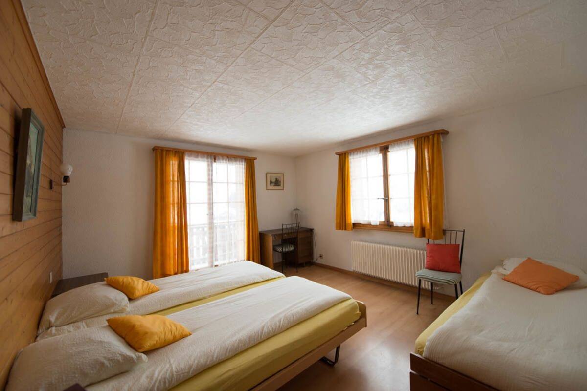 A room with two beds, a desk, and a chair.