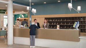 Een receptiegedeelte met een balie, een servicepunt en een zithoek met stoelen.
