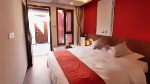 A hotel room with a large bed, a red accent wall, and a view through a door. - HongYi Home (Beijing)