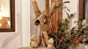 A rustic stone well with a wooden structure above it, a small figurine, and a potted plant with red berries. - HongYi Home (Beijing)