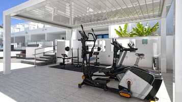 Un gimnasio moderno con máquinas de cardio, pesas y una escalera que lleva a niveles superiores.