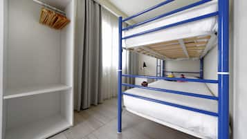 Una cama nido con barandillas azules, un armario blanco y un espejo en la pared.