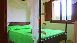 Una cama individual con cubrecama verde y dosel blanco.