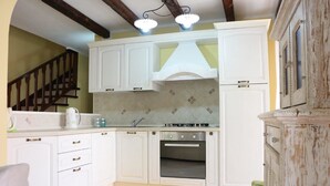 A kitchen with white cabinets, a stove, and a sink. - Residenza del Comandante (Santa Teresa di Gallura)