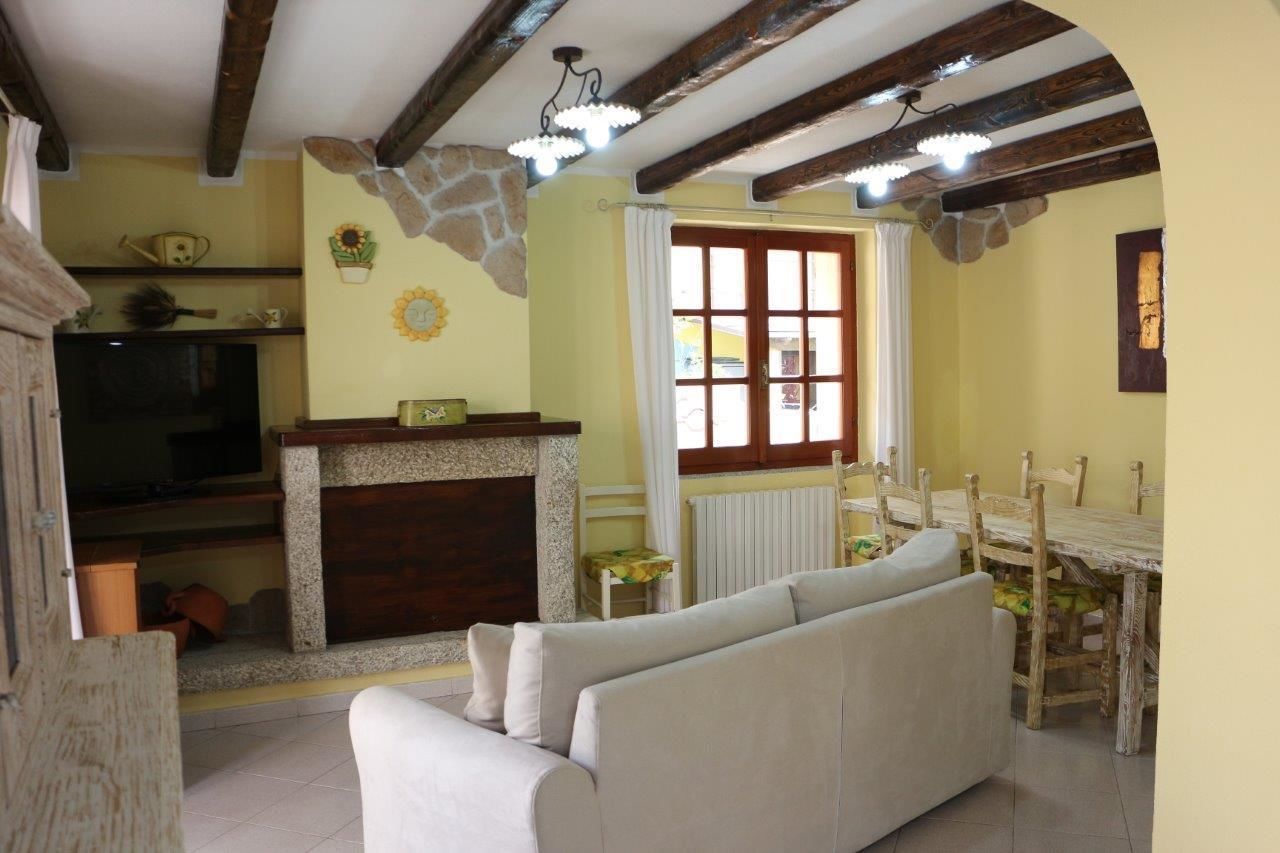 Una sala de estar acogedora con chimenea, un sofá, una mesa de comedor con sillas y un televisor.