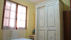 A bedroom with a bed, a wardrobe, and a window with curtains. - Residenza del Comandante (Santa Teresa di Gallura)