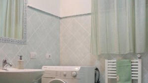 A bathroom with a washing machine, sink, and toilet. - Residenza del Comandante (Santa Teresa di Gallura)