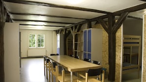 A room with a long wooden table and chairs, bunk beds, and lockers. - Gästehaus Klein Grönau (Lübeck)