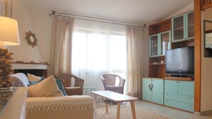 A living room with a sofa, chairs, a table, a television, and a cabinet. - Residence Ostro (Santa Teresa di Gallura)