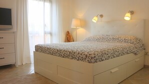 A bedroom with a bed, a bedside lamp, a TV, and a window with curtains. - Residence Ostro (Santa Teresa di Gallura)