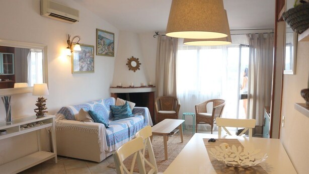 A living room with a sofa, chairs, a table, and a fireplace. - Residence Ostro (Santa Teresa di Gallura)