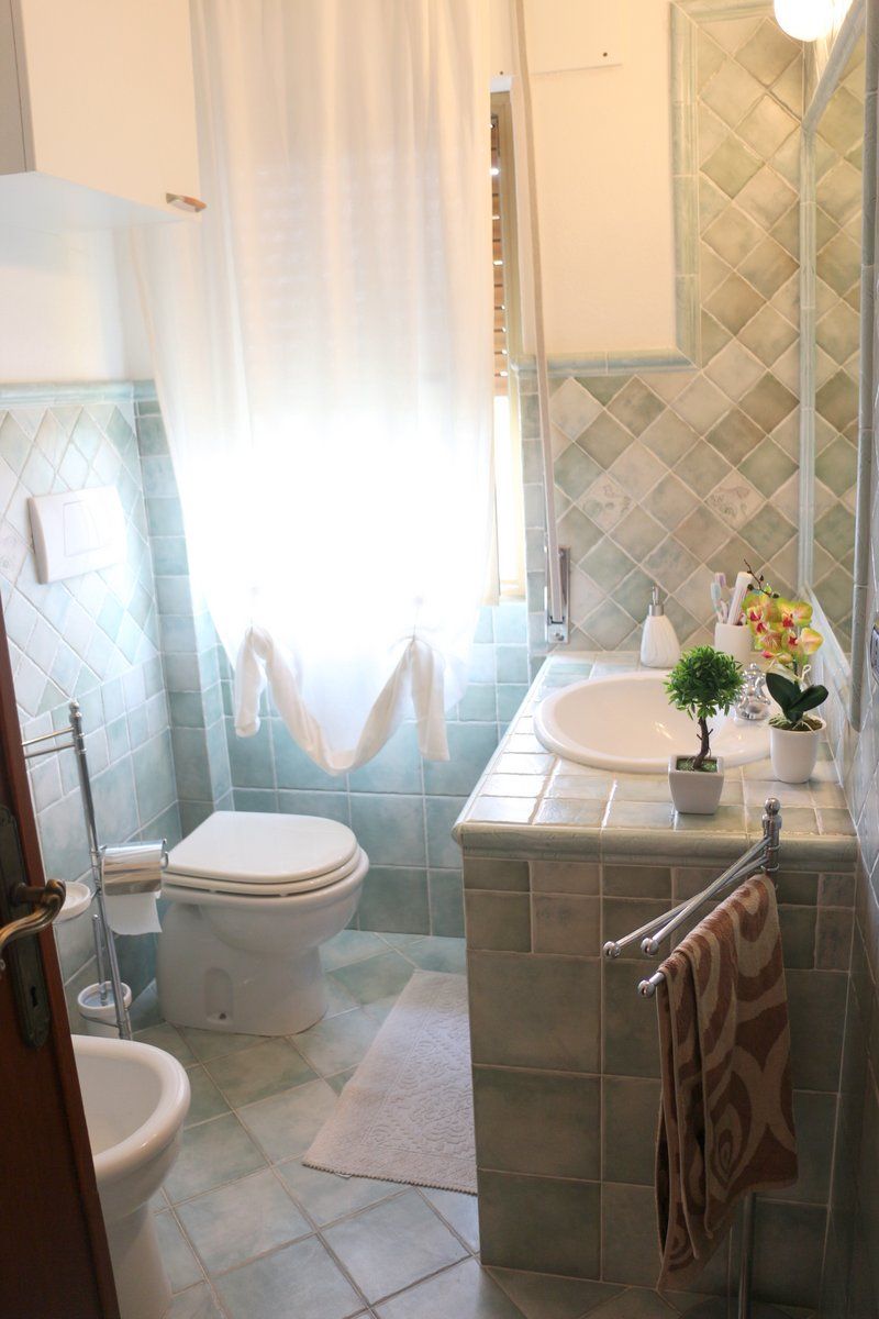 A bathroom with a toilet, bidet, sink, and a shower area.