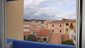 A view of a town with terracotta-roofed buildings, a hillside in the background, and a blue balcony railing. - Residence Levante (Santa Teresa di Gallura)