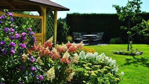 A garden with a wooden pergola, a lawn, and a table with chairs. - Ferienwohnung Familie Kappauf & Petrik (Friedenfels)