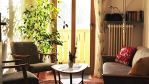 A living room with a sofa, armchair, and a table with a vase. - Ferienwohnung Familie Kappauf & Petrik (Friedenfels)