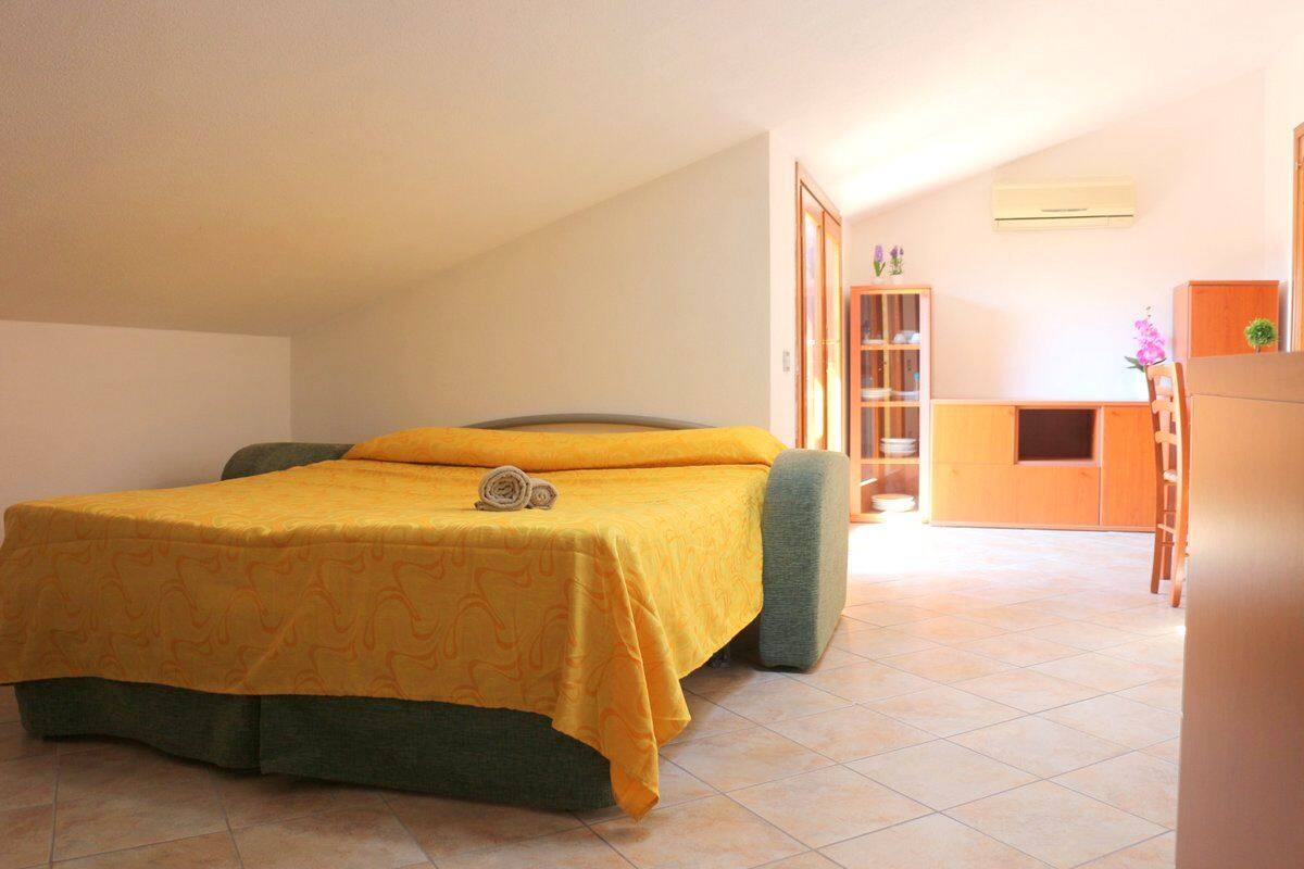A bedroom with a bed, a small desk, and a cabinet.