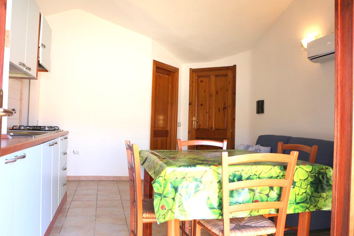 Une cuisine de taille réduite comprenant une table à manger, des chaises et une cuisinière.
