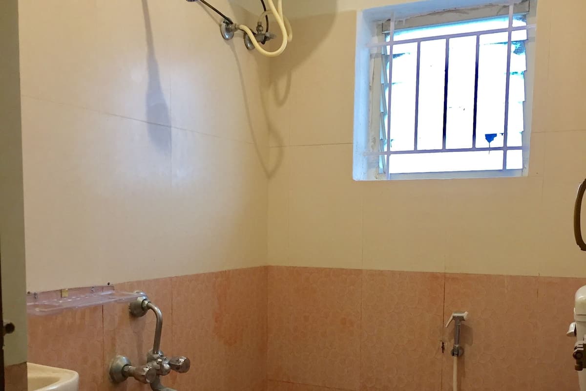 Une petite salle de bain avec des toilettes, une douche et une fenêtre.