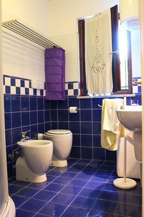 Ein Badezimmer mit zwei Toiletten, einem Waschbecken und einem Fenster mit Vorhang.