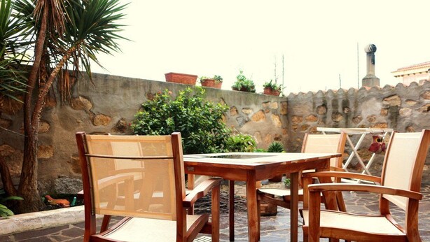 An outdoor patio with wooden furniture and stone flooring. - Casette del Centro (Santa Teresa di Gallura)