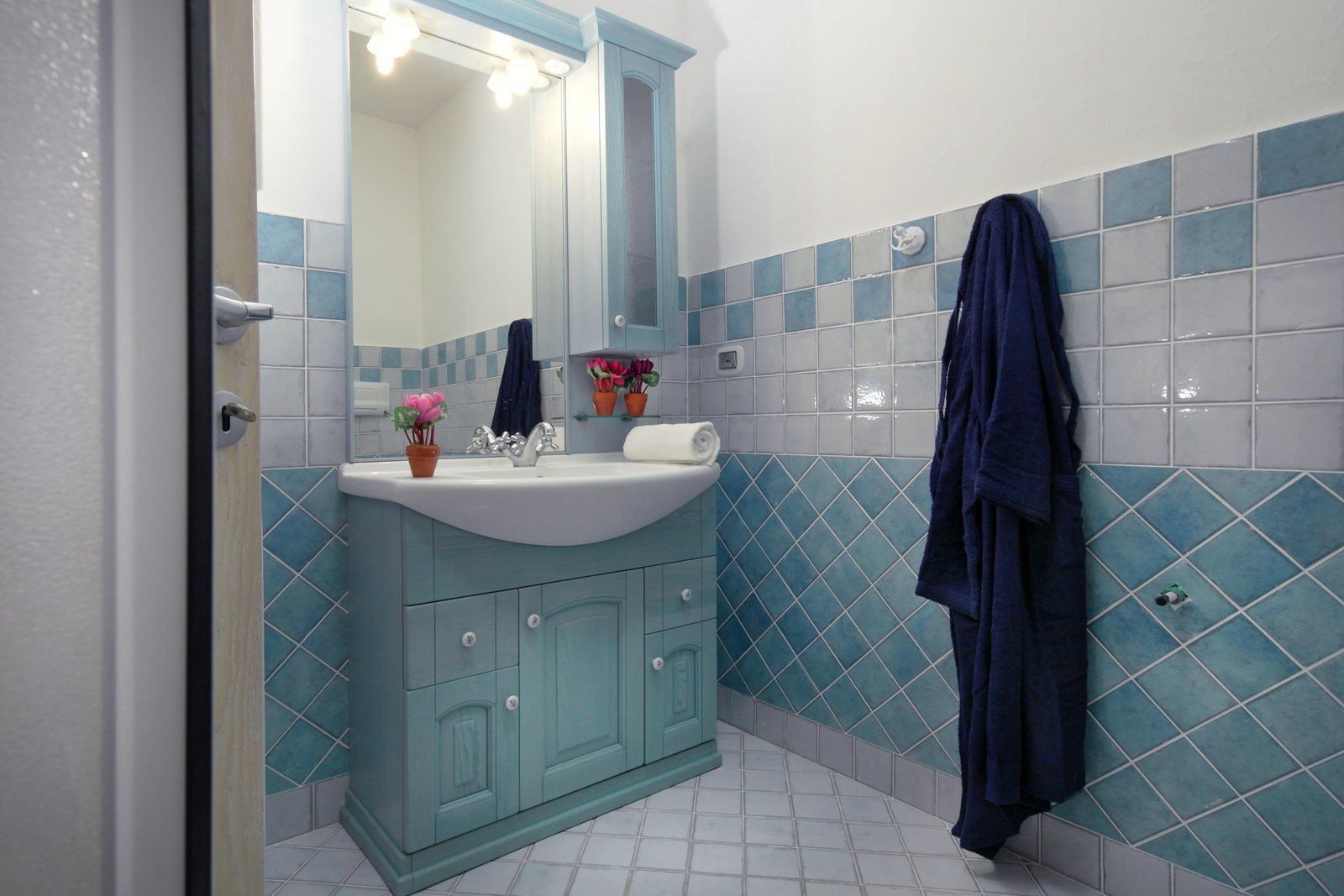 A bathroom with a sink, mirror, and blue tiles.