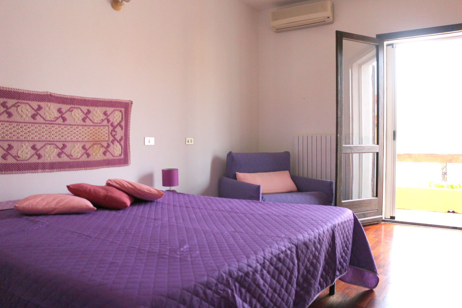 Ein Schlafzimmer mit einem Bett, einem Sessel, einer Lampe und einem Fenster.