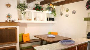 A kitchen with a wooden table, a bench, and a tiled backsplash. - Casa Seby (Santa Teresa di Gallura)