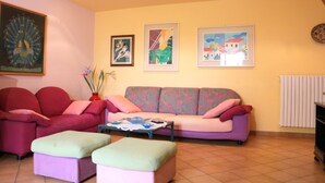 A living room with a sofa, two armchairs, a coffee table, and a painting of a peacock on the wall. - Casa Seby (Santa Teresa di Gallura)