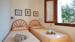 A bedroom with two single beds, a window with a curtain, and three framed pictures on the wall. - Villetta Sartori (Santa Teresa di Gallura)