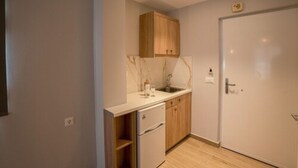 A compact kitchen with wooden cabinets, a marble countertop, and a white refrigerator. - Domus Alta (Zakynthos)