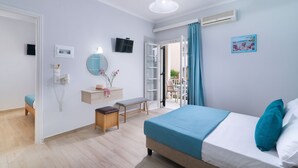 A bedroom with a bed, bedside table, and a small bench. There is a TV mounted on the wall and a window with curtains. - Domus Alta (Zakynthos)
