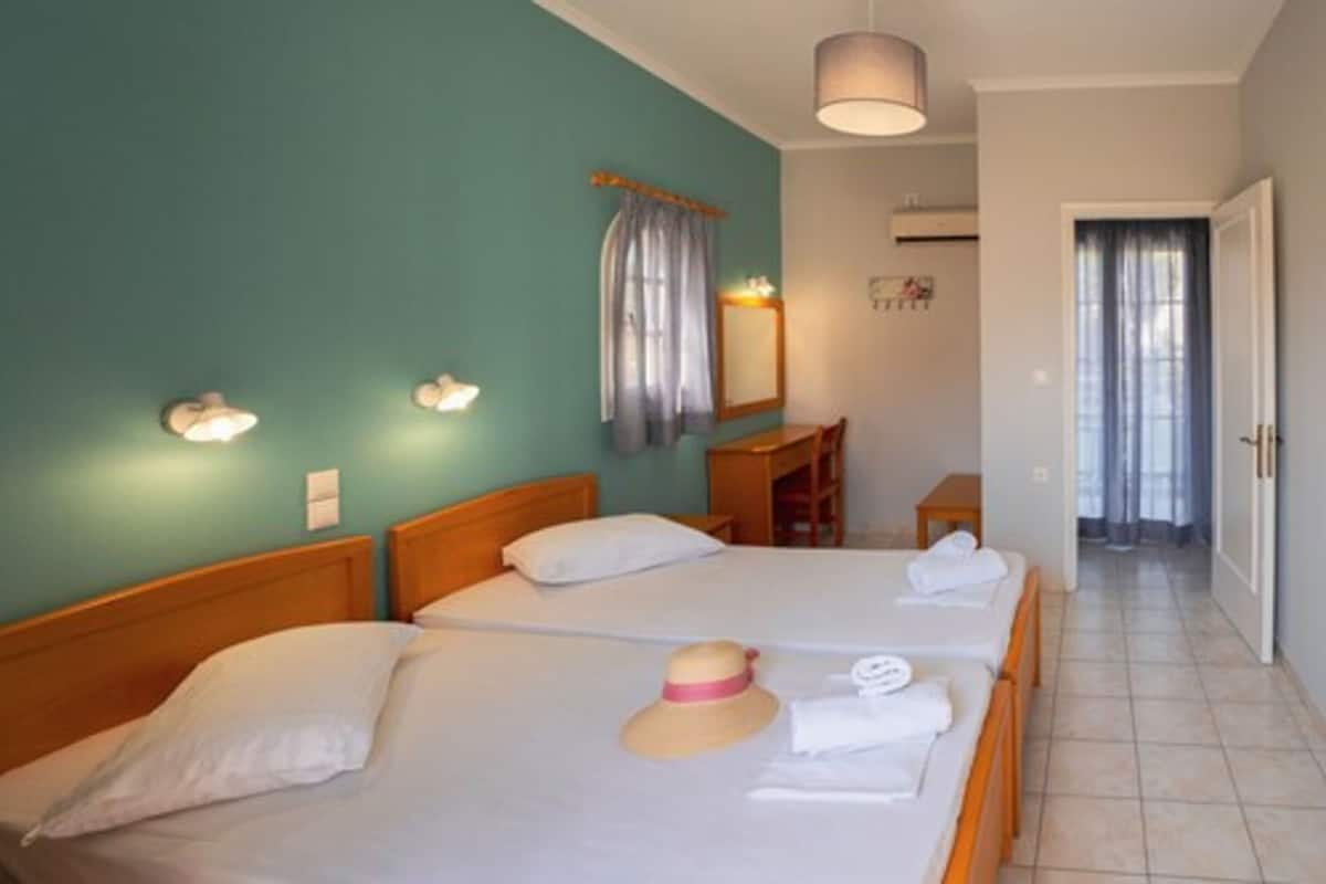 Habitación de hotel con dos camas, un escritorio y un espejo.