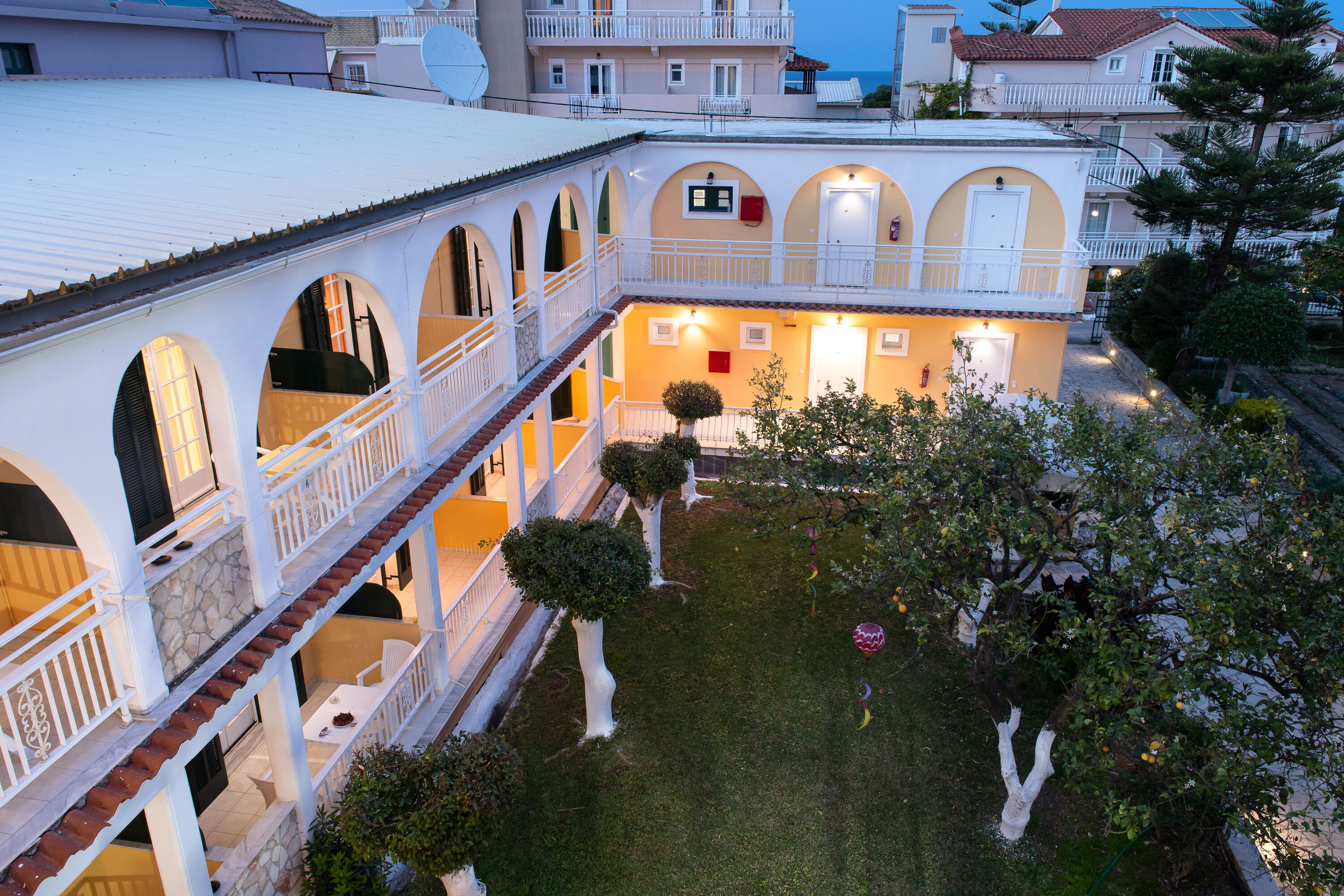 A courtyard with a white building featuring multiple balconies and arched windows.