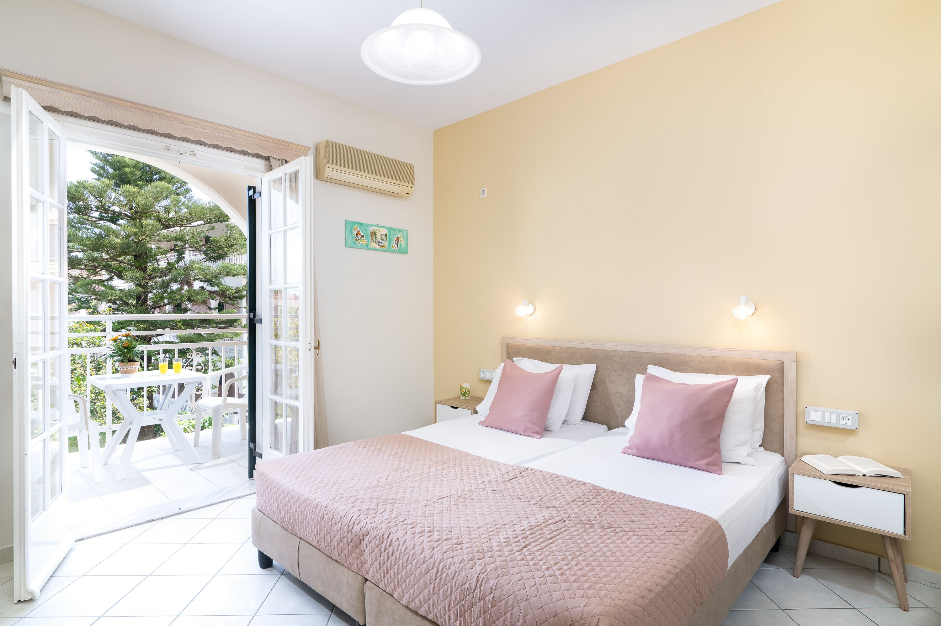 Un dormitorio con cama, mesitas de noche y vistas a un patio exterior.