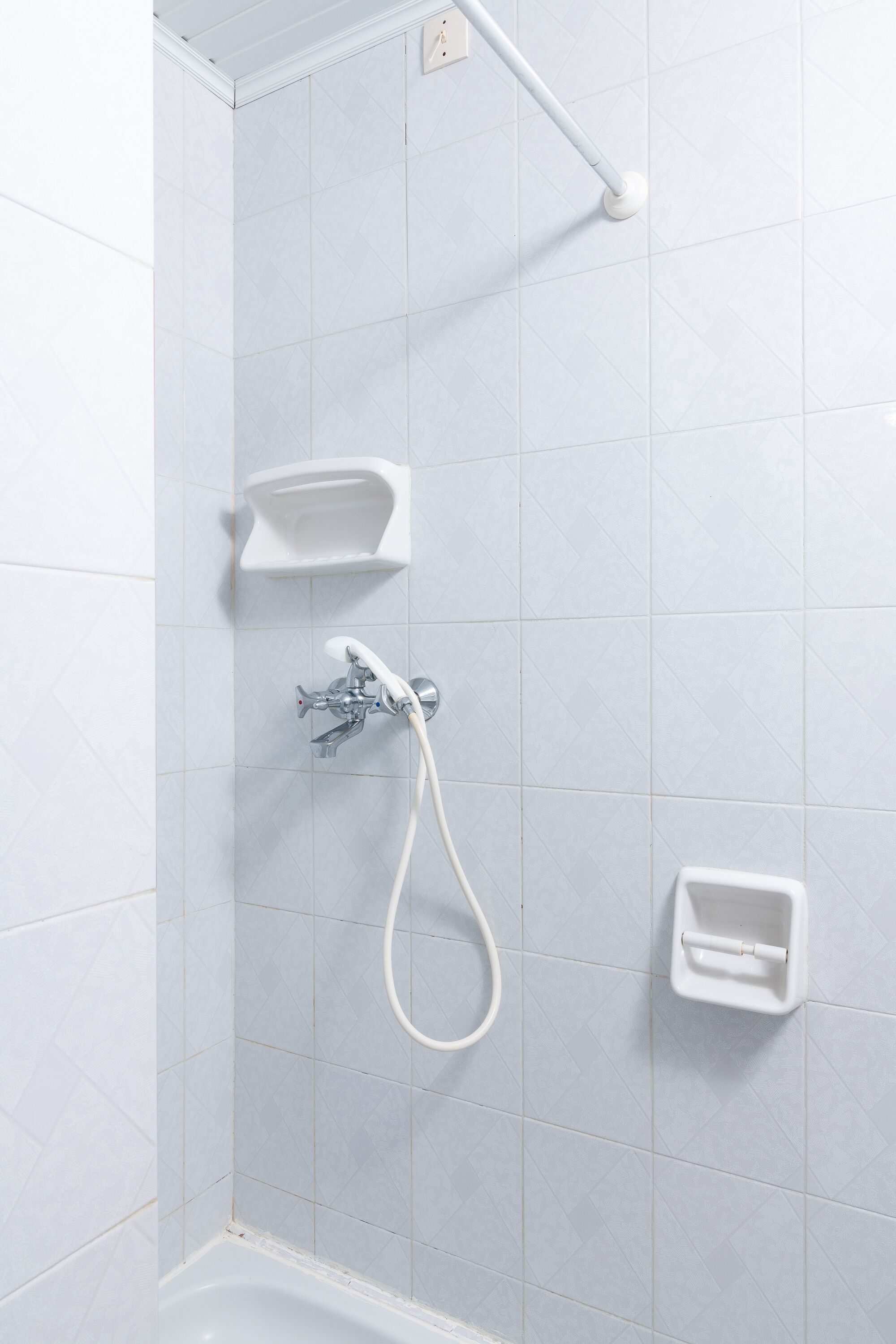 A shower area with a handheld showerhead, a handheld shower attachment, and a soap dish.