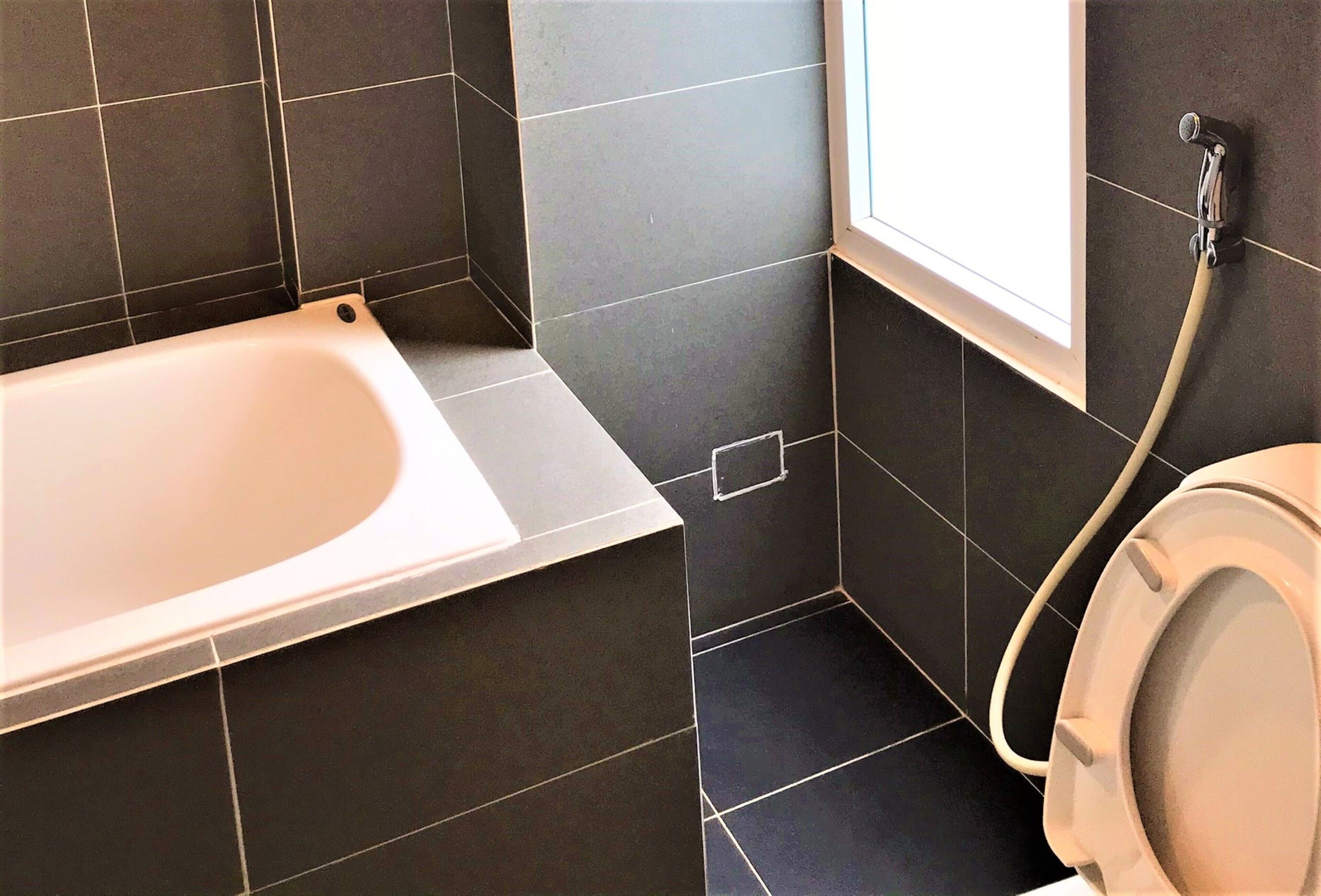 Et badeværelse med badekar, toilet og et vindue.