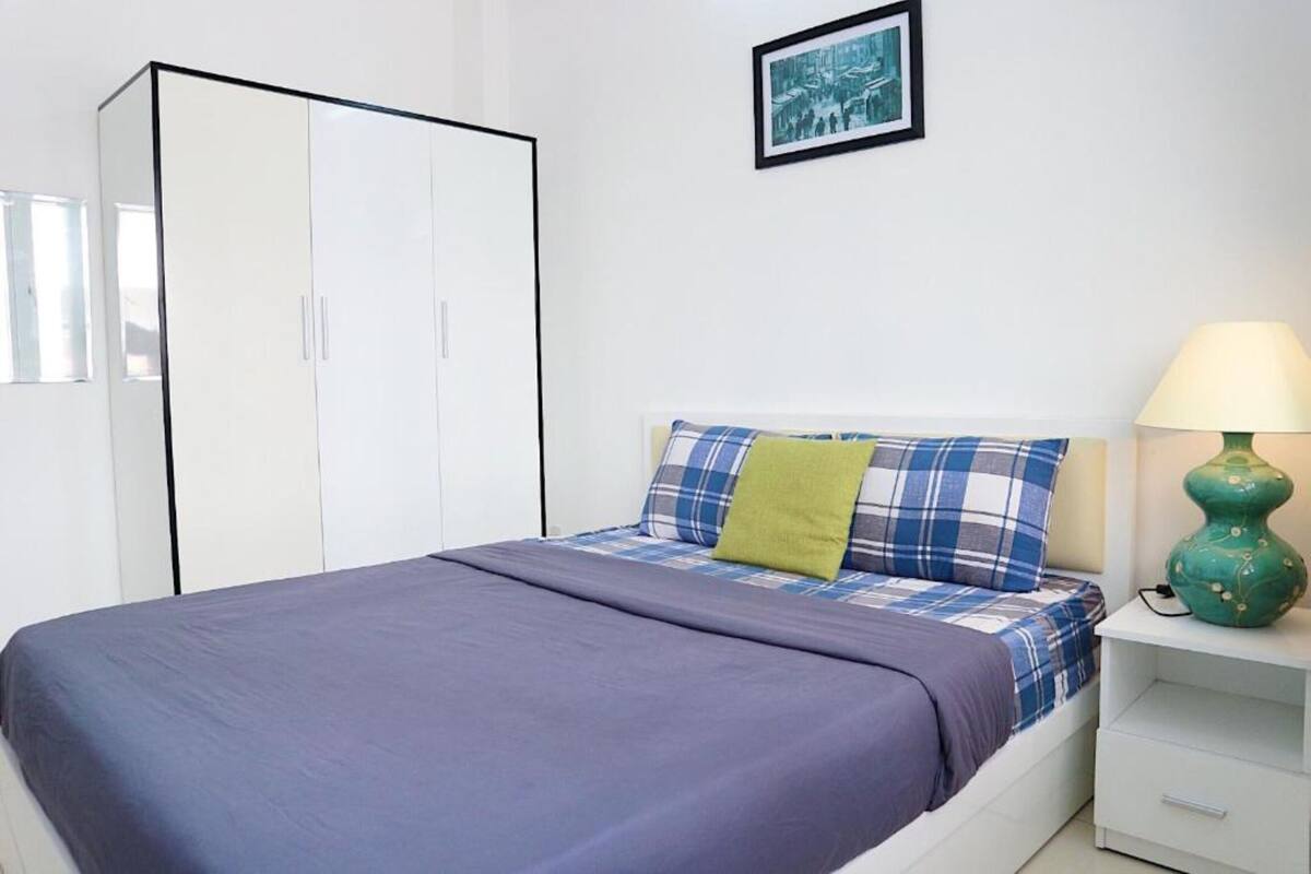 Ein Schlafzimmer mit Bett, Kleiderschrank, Nachttisch und Lampe.