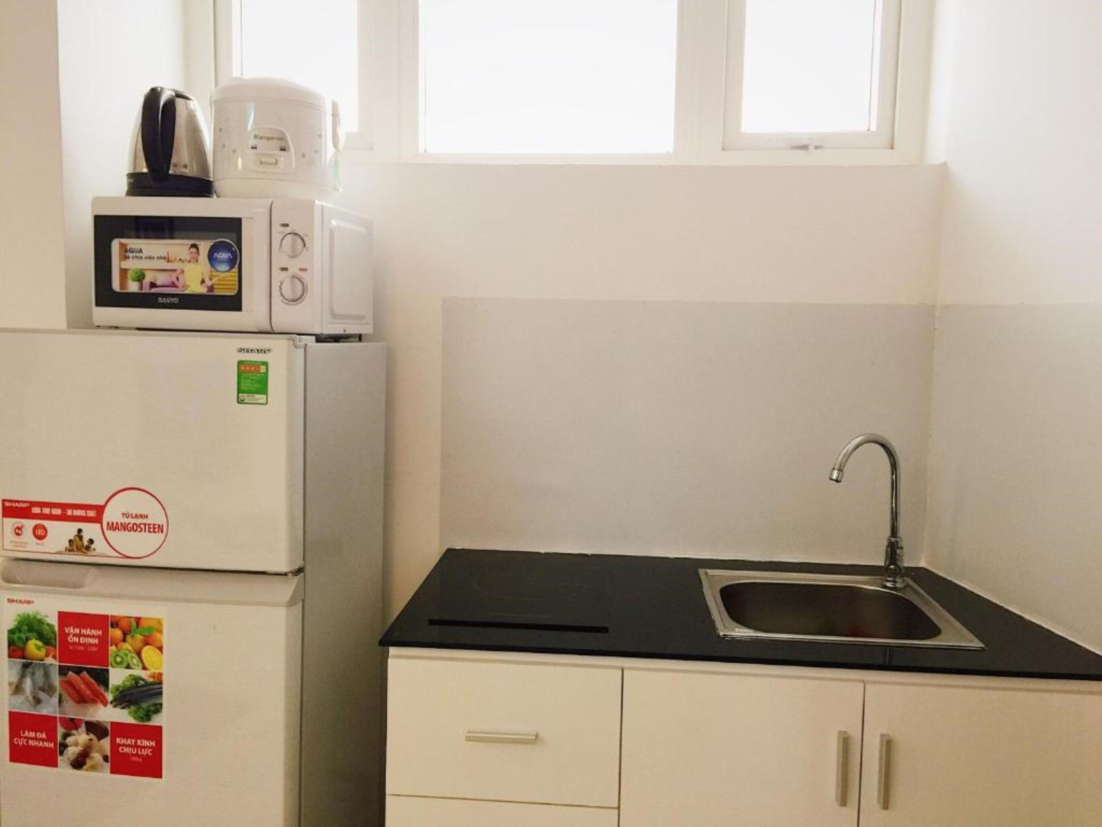 A compact kitchen with a refrigerator, microwave, and a sink.
