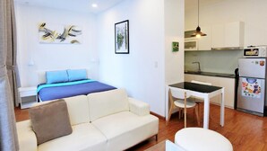 Um espaço compacto com cama, sofá, mesa de jantar e cozinha compacta.