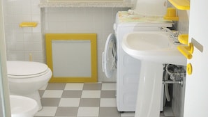 A bathroom with a toilet, a washing machine, and a sink. - Residence Grecale (Santa Teresa di Gallura)