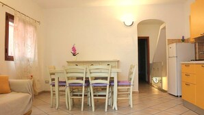 A compact living space with a dining area, kitchenette, and a sofa. - Gemelle di Cairoli (Santa Teresa di Gallura)