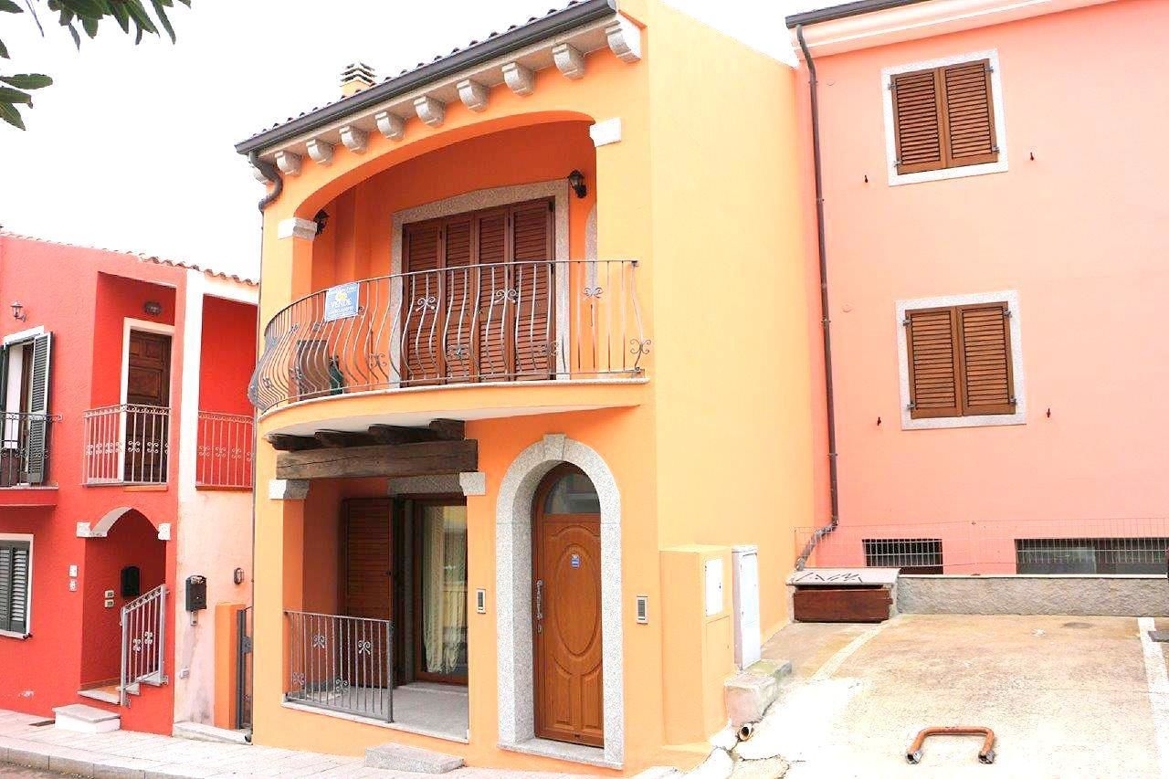 Um edifício de dois andares com uma varanda, uma porta de madeira e um pequeno alpendre.