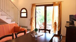 A dining area with a wooden table, chairs, a sofa, and a television. - Gemelle di Cairoli (Santa Teresa di Gallura)