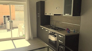 A compact kitchen with a gas stove, oven, and cabinets. - Tiffany House (Santa Teresa di Gallura)