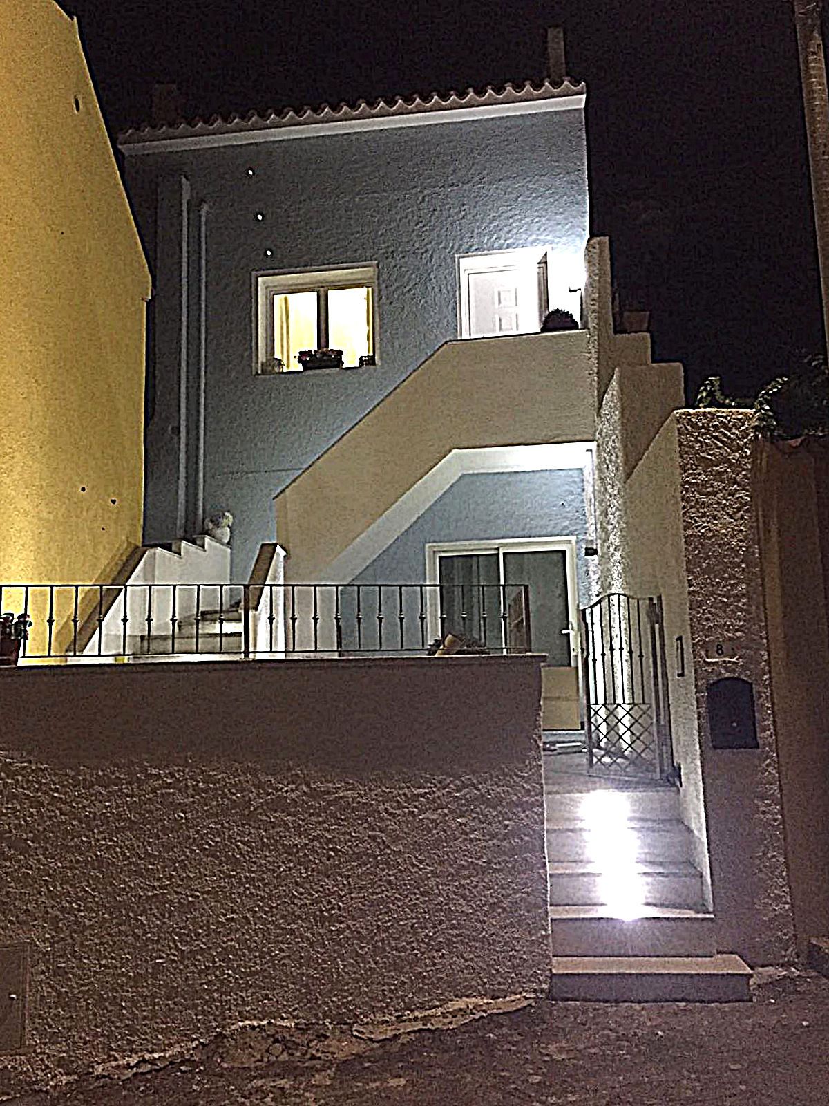 Un edificio con una escalera que lleva a una puerta, una ventana y un pequeño balcón.