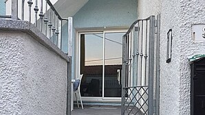 A staircase leading to a glass door with a metal gate, a chair, and a small table outside. - Tiffany House (Santa Teresa di Gallura)