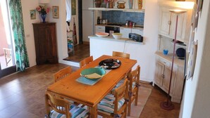 Une cuisine compacte avec une table et des chaises en bois, un petit coin repas et un sol carrelé.
