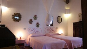Une chambre à coucher avec deux lits, dont un lit à baldaquin, des miroirs décoratifs et une horloge.